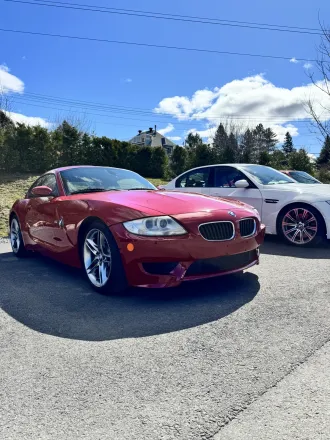 BMW Z4 rouge carmin, trois quarts avant, dans le stationnement de la concession.