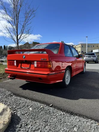 BMW M3 E30 rouge, vue arrière, aileron surélevé.