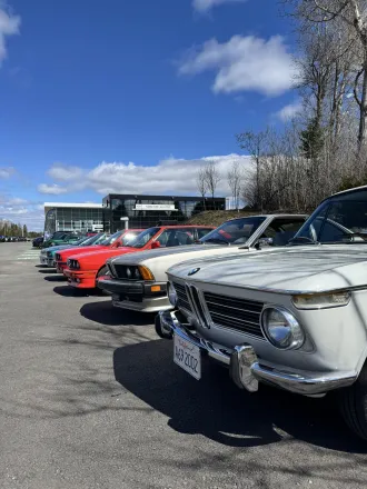 Alignement de BMW de collection, BMW 2002 blanche au premier plan, calandre chromée et écusson BMW.