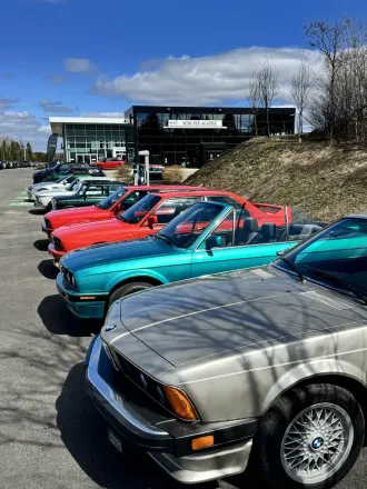 Alignement de BMW de collection devant la concession, BMW E30 argent au premier plan.