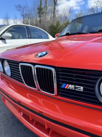 Calandre à double haricot et badge M3 sur le capot de la BMW M3 E30 rouge.